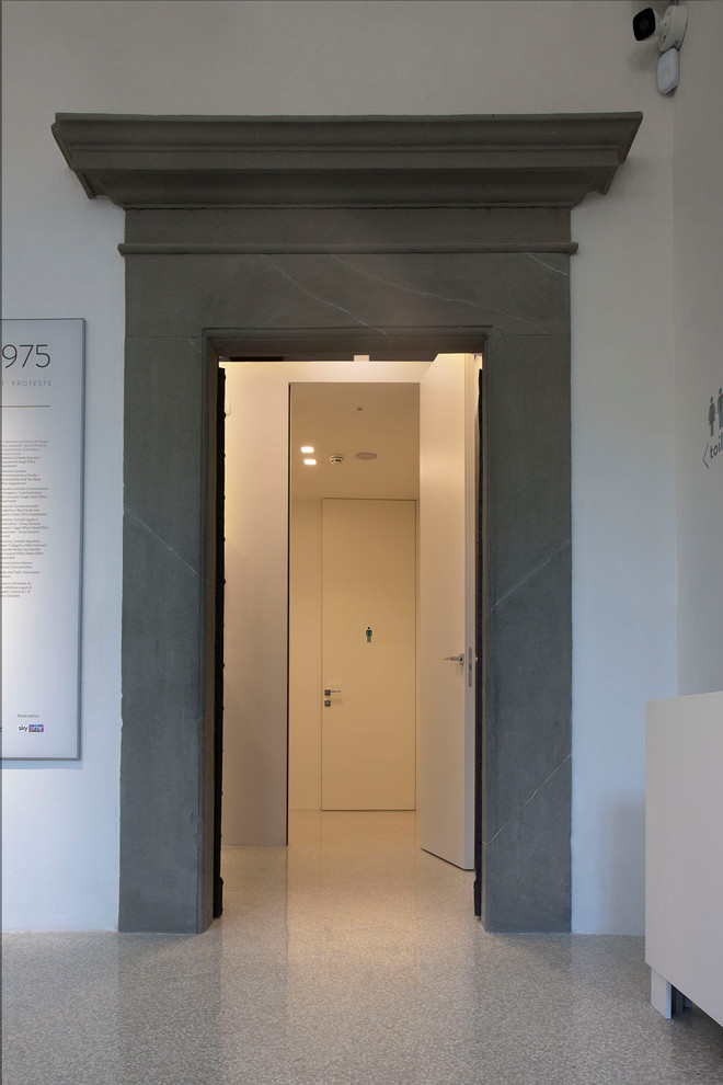 Photo of a large contemporary cloakroom in Florence with beaded cabinets, white walls, concrete flooring and grey floors.