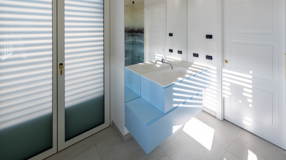 Design ideas for a large contemporary cloakroom in Milan with flat-panel cabinets, turquoise cabinets, a wall mounted toilet, multi-coloured tiles, porcelain tiles, white walls, porcelain flooring, an integrated sink, engineered stone worktops, beige floors and white worktops.