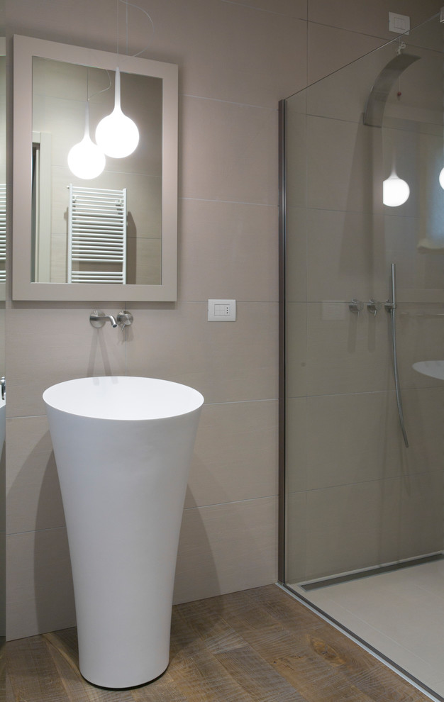 This is an example of a small modern cloakroom in Milan with recessed-panel cabinets, a two-piece toilet, porcelain tiles, dark hardwood flooring and a pedestal sink.