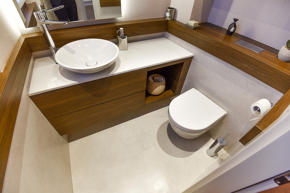 Design ideas for a small contemporary cloakroom in Other with beaded cabinets, beige cabinets, a wall mounted toilet, beige tiles, porcelain tiles, beige walls, porcelain flooring, a vessel sink, limestone worktops, beige floors and beige worktops.