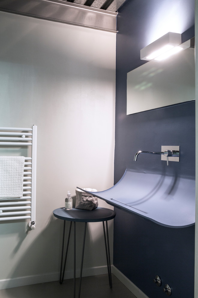 Inspiration for a small modern cloakroom in Other with blue cabinets, a wall mounted toilet, blue walls, concrete flooring, a wall-mounted sink, solid surface worktops and grey floors.