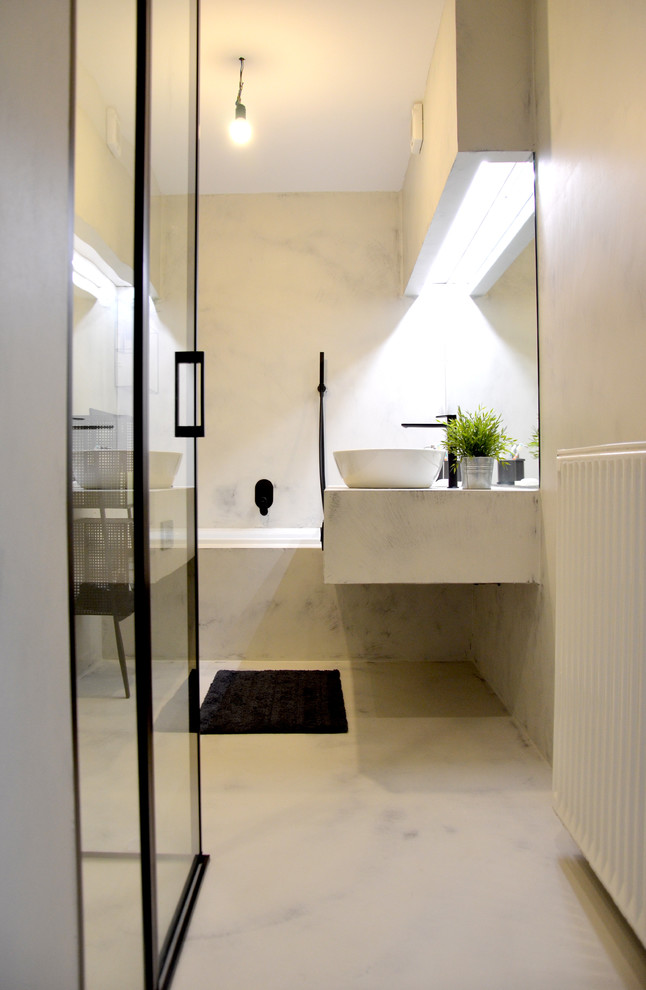 Aménagement d'un petit WC suspendu industriel avec un placard sans porte, des portes de placard noires, un carrelage gris, un mur gris, sol en béton ciré, une vasque, un plan de toilette en béton, un sol gris et un plan de toilette gris.