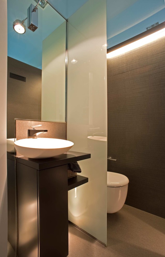 Cette image montre un petit WC et toilettes design avec un placard à porte plane, des portes de placard noires et un sol beige.