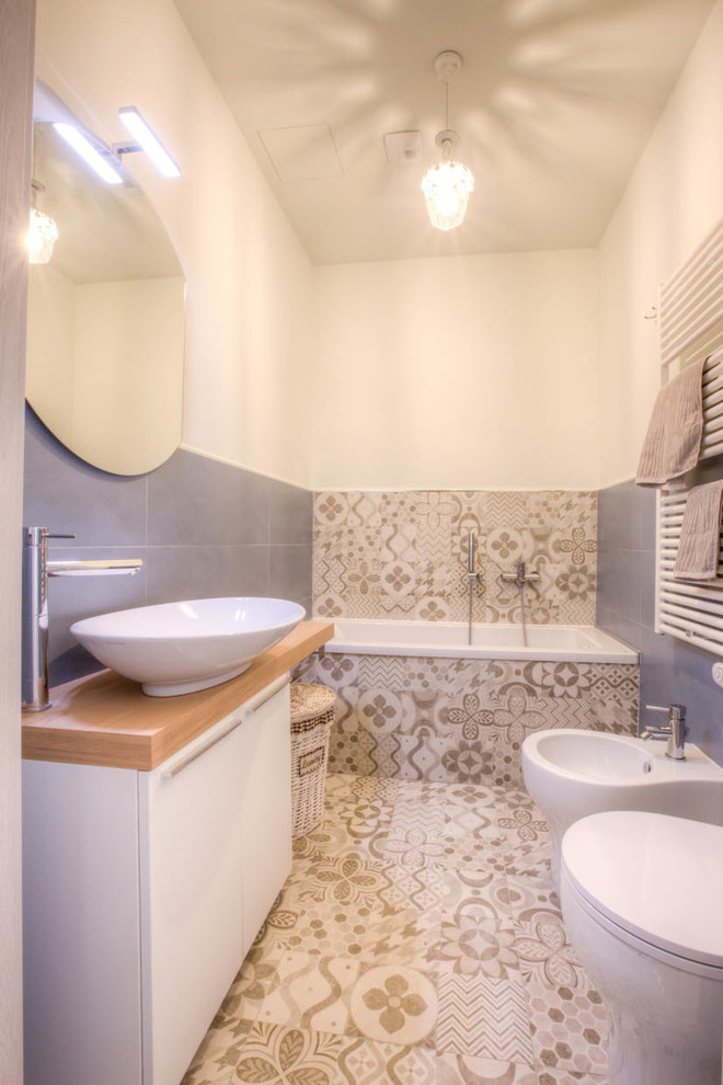 Photo of a small mediterranean cloakroom in Other with flat-panel cabinets, white cabinets, a one-piece toilet, blue tiles, porcelain tiles, white walls, porcelain flooring, a vessel sink, wooden worktops and multi-coloured floors.