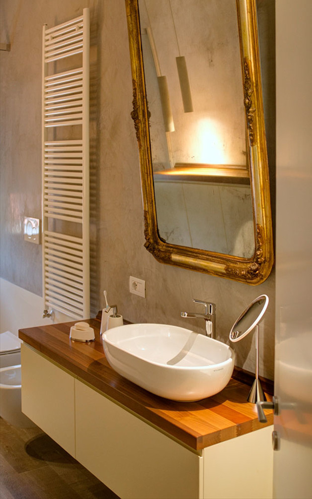 Cette photo montre un grand WC suspendu moderne en bois brun avec un placard à porte plane, un mur gris, un sol en bois brun, une vasque, un plan de toilette en bois, un sol marron et un plan de toilette marron.