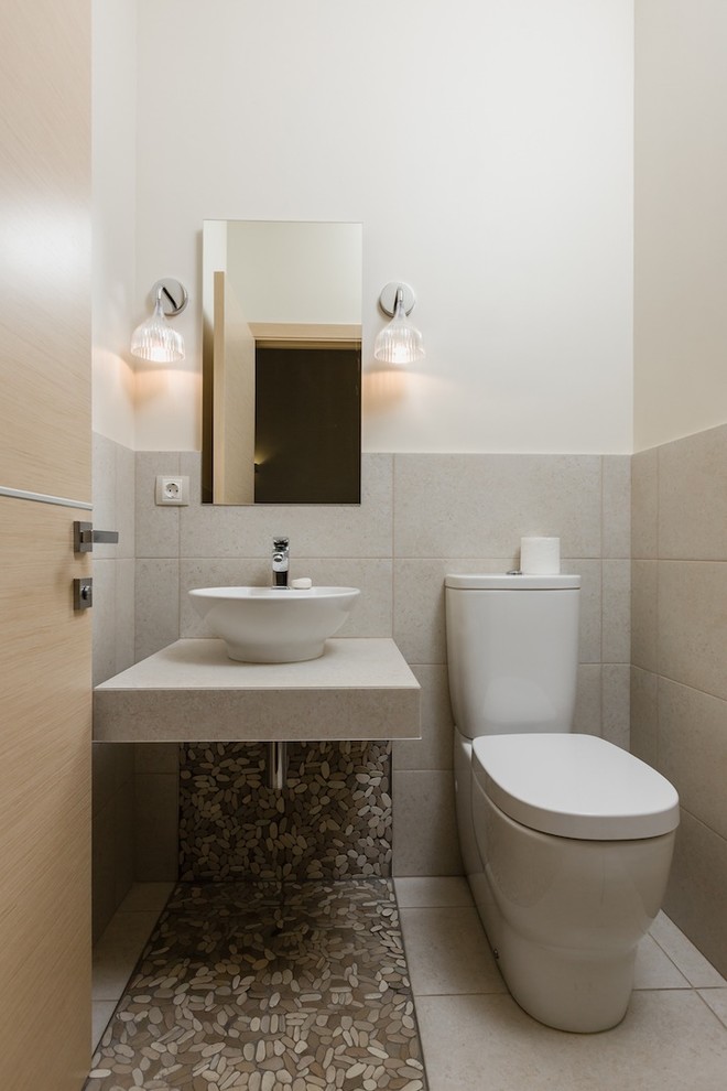 Kleine Landhausstil Gästetoilette mit Toilette mit Aufsatzspülkasten, beigen Fliesen, Porzellanfliesen, weißer Wandfarbe, Kiesel-Bodenfliesen und Aufsatzwaschbecken in Sonstige
