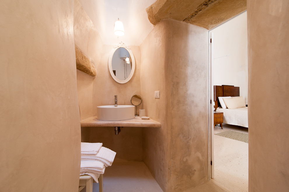 バーリにあるサンタフェスタイルのおしゃれなトイレ・洗面所 (ベージュの壁、ベッセル式洗面器、ベージュの床) の写真