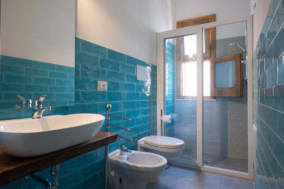 Inspiration pour un WC suspendu design en bois clair de taille moyenne avec un carrelage bleu, des carreaux de céramique, un mur blanc, un sol en carrelage de porcelaine, une vasque, un plan de toilette en bois, un sol gris et un plan de toilette marron.