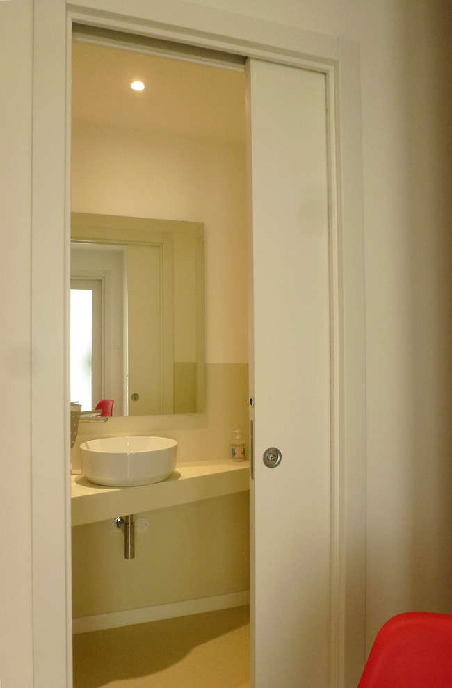 Kleine Moderne Gästetoilette mit Wandtoilette, beigen Fliesen, beiger Wandfarbe, Linoleum, Aufsatzwaschbecken, beigem Boden und beiger Waschtischplatte in Sonstige
