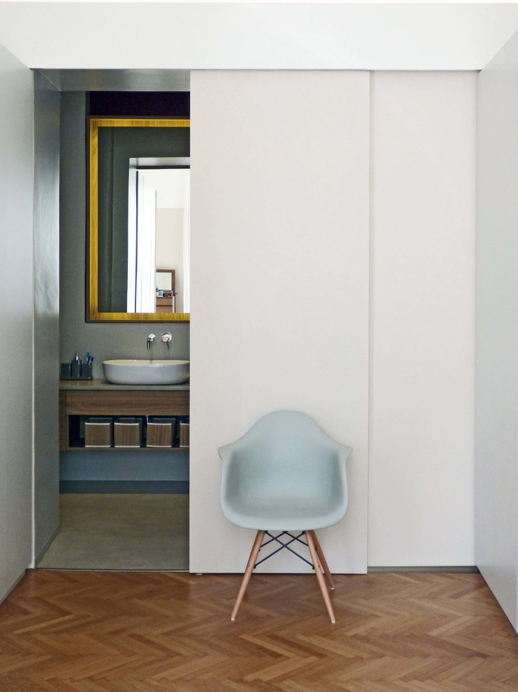 Inspiration for a medium sized contemporary cloakroom in Other with flat-panel cabinets, light wood cabinets, a two-piece toilet, grey walls, medium hardwood flooring, a vessel sink, concrete worktops, yellow floors and grey worktops.