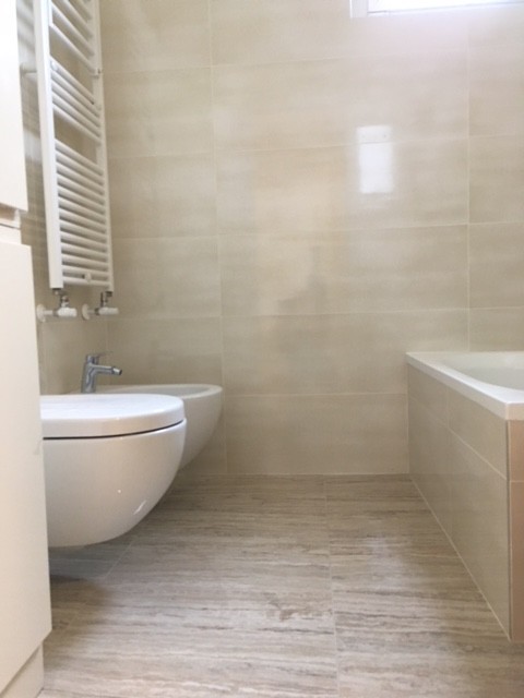 Modern inredning av ett litet toalett, med släta luckor, beige skåp, en vägghängd toalettstol, beige kakel, beige väggar, klinkergolv i porslin, ett integrerad handfat, bänkskiva i kvartsit och beiget golv