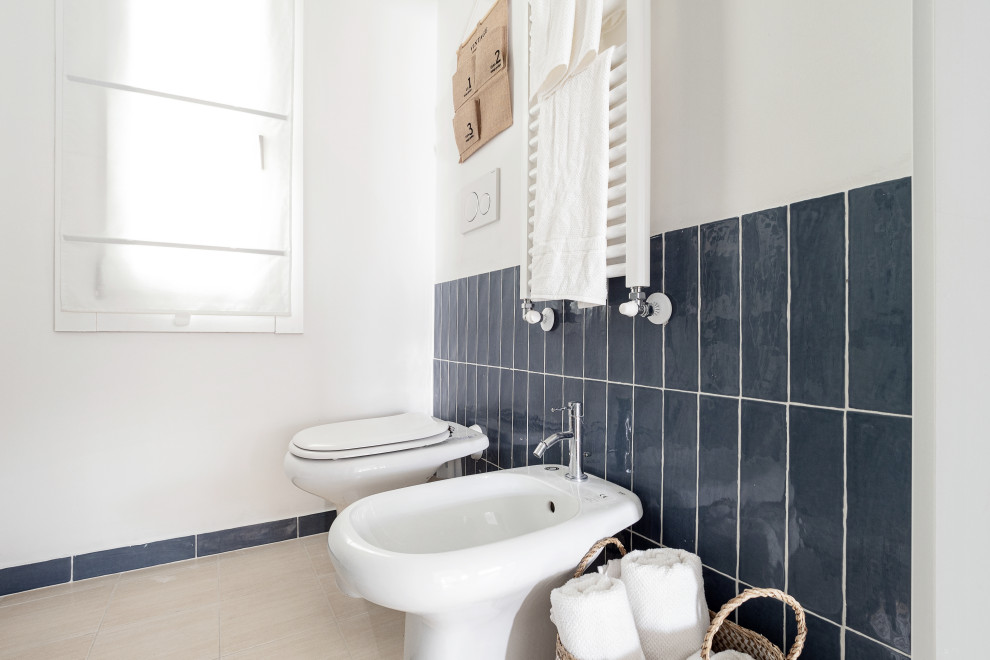 Immagine di un piccolo bagno di servizio tropicale con ante beige, WC a due pezzi, piastrelle blu, piastrelle a listelli, pareti bianche, pavimento in laminato, lavabo a bacinella e pavimento bianco