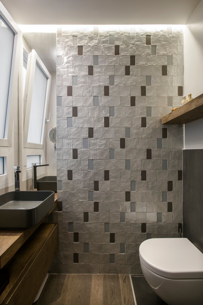 Kleine Eklektische Gästetoilette mit Wandtoilette, farbigen Fliesen, Mosaikfliesen, dunklem Holzboden, Aufsatzwaschbecken und Waschtisch aus Holz in Rom
