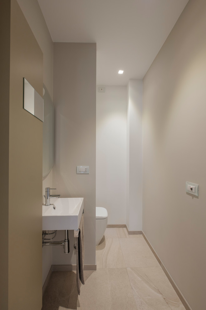 Esempio di un piccolo bagno di servizio minimalista con ante lisce, WC monopezzo, pareti grigie, pavimento in gres porcellanato e lavabo sospeso