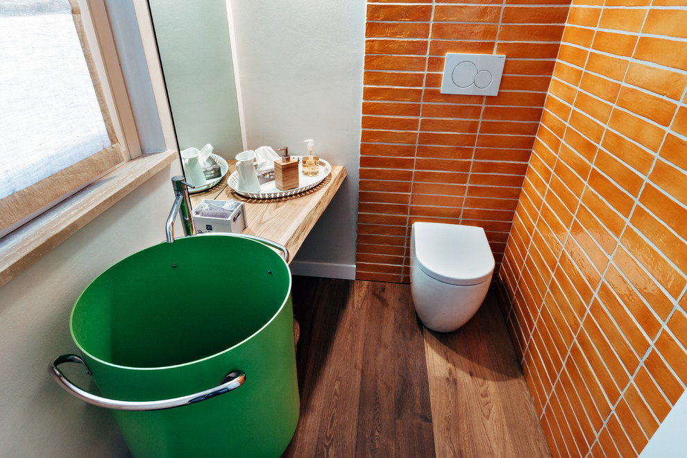 Idée de décoration pour un petit WC et toilettes design avec des portes de placard noires, un carrelage jaune, des carreaux de céramique, sol en béton ciré et un sol noir.
