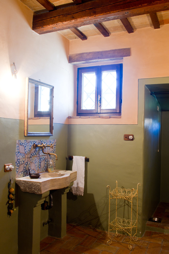 На фото: туалет среднего размера в стиле кантри с темными деревянными фасадами, терракотовой плиткой, зелеными стенами, полом из терракотовой плитки, монолитной раковиной, столешницей из известняка и разноцветной плиткой с