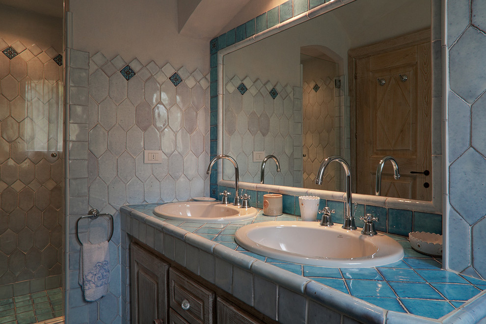 На фото: большой туалет в средиземноморском стиле с фасадами с декоративным кантом, искусственно-состаренными фасадами, синей плиткой, керамической плиткой, накладной раковиной и столешницей из плитки