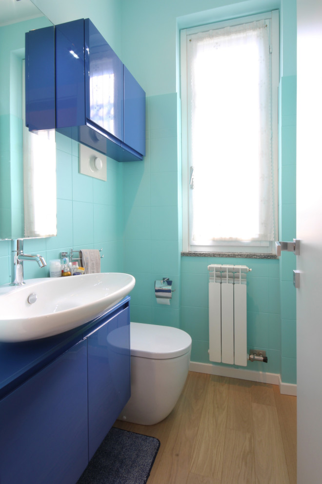 Idéer för att renovera ett litet funkis blå blått toalett, med släta luckor, blå skåp, en toalettstol med separat cisternkåpa, keramikplattor, flerfärgade väggar, mellanmörkt trägolv, ett fristående handfat, träbänkskiva, gult golv och flerfärgad kakel