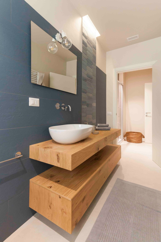 Idée de décoration pour un WC et toilettes design avec un carrelage bleu, mosaïque et un sol beige.