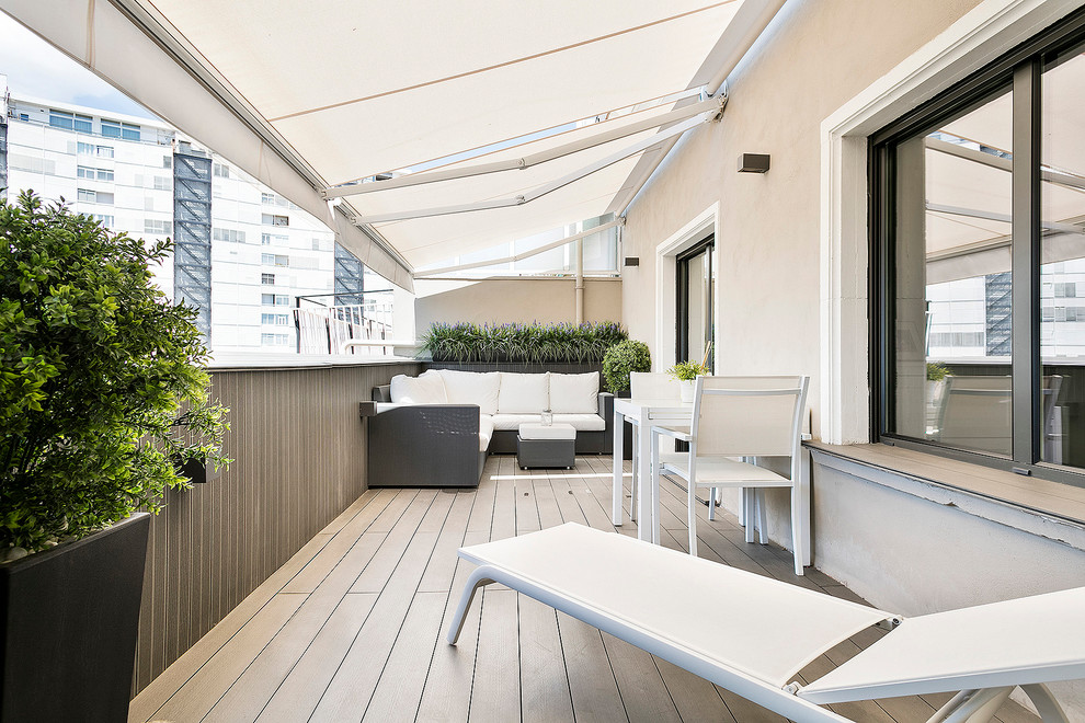 Photo of a medium sized modern balcony in Barcelona with an awning and a potted garden.