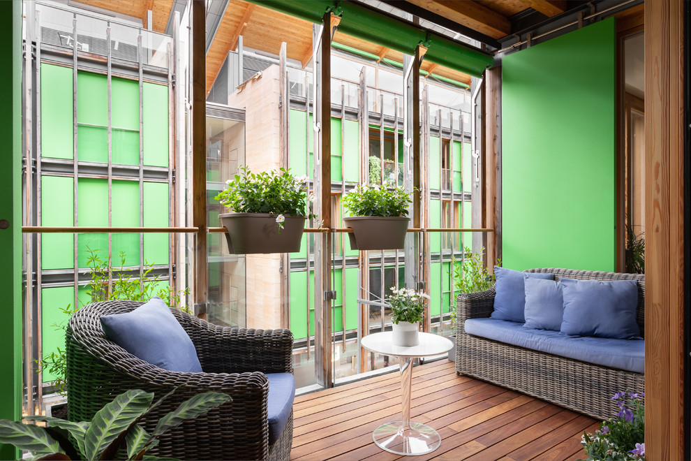 Idée de décoration pour un petit balcon design avec des plantes en pot, un garde-corps en verre et une extension de toiture.