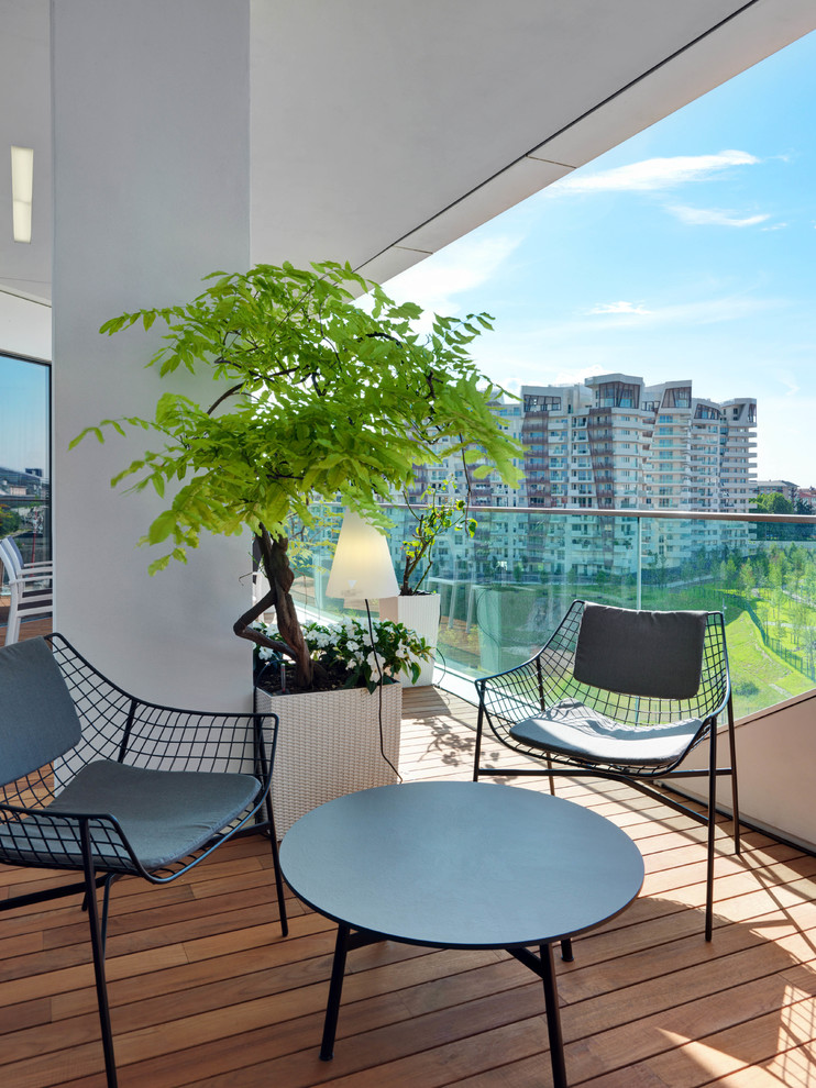 Cette photo montre un balcon tendance de taille moyenne avec des plantes en pot, une extension de toiture et un garde-corps en verre.