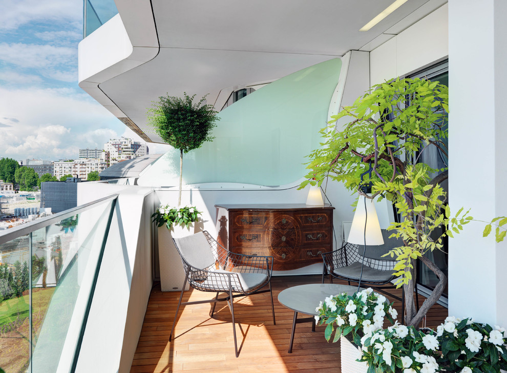 Aménagement d'un balcon contemporain de taille moyenne avec des plantes en pot, une extension de toiture et un garde-corps en verre.