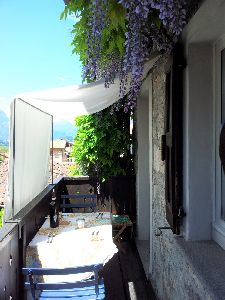 На фото: маленький балкон и лоджия в стиле рустика с перегородкой для приватности, козырьком и деревянными перилами для на участке и в саду с