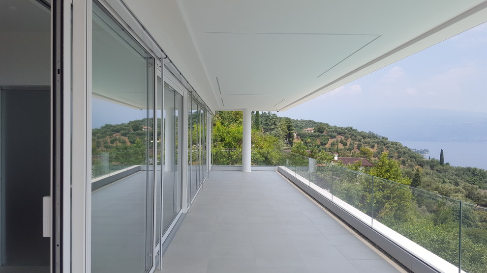 Immagine di un grande balcone minimalista con parapetto in vetro