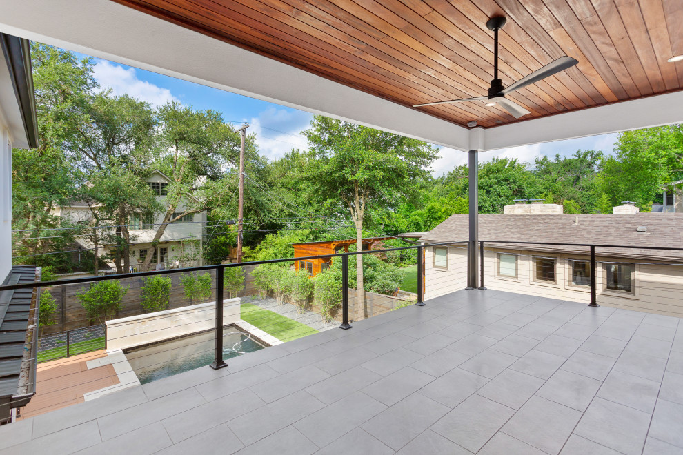Cette photo montre un grand balcon tendance avec une extension de toiture et un garde-corps en câble.