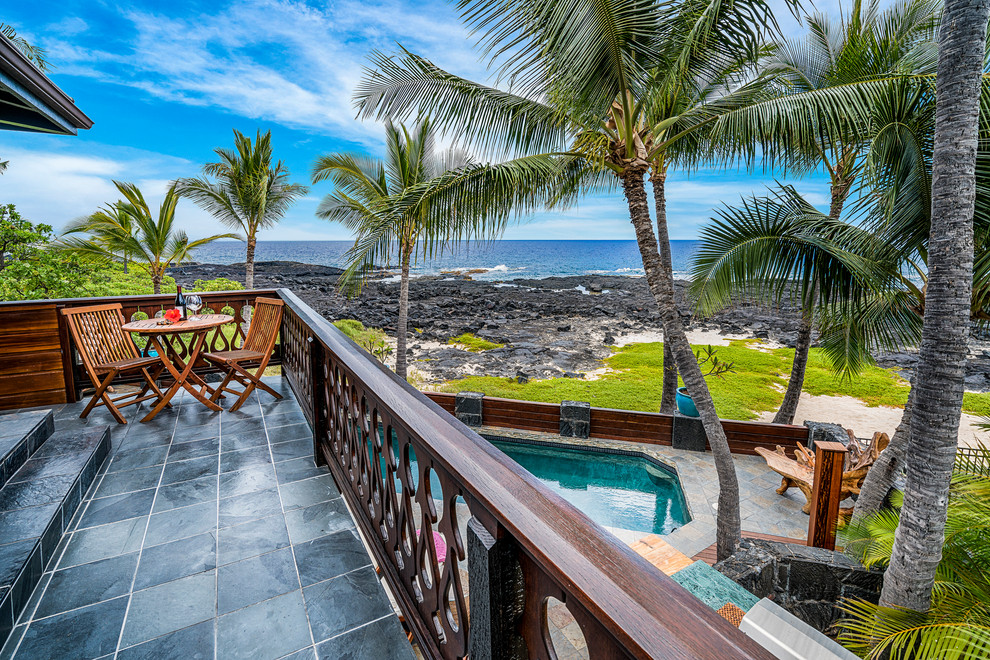 ハワイにある中くらいなトロピカルスタイルのおしゃれなベランダ・バルコニー (日よけなし、木材の手すり) の写真