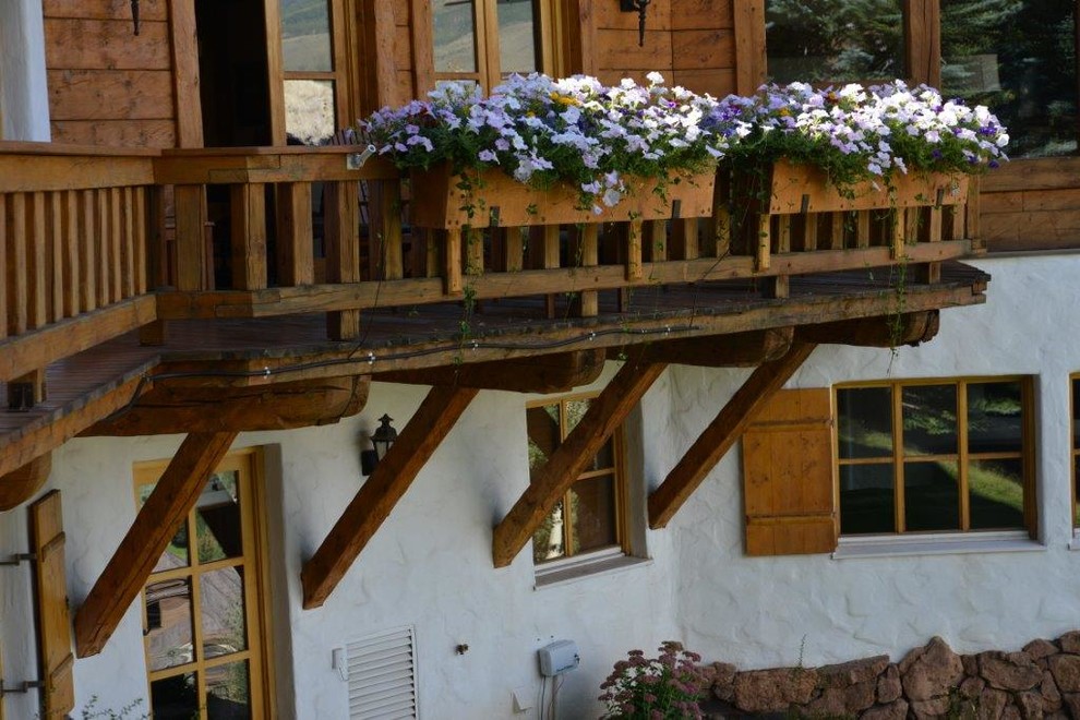 Inredning av en rustik liten balkong, med utekrukor och räcke i trä