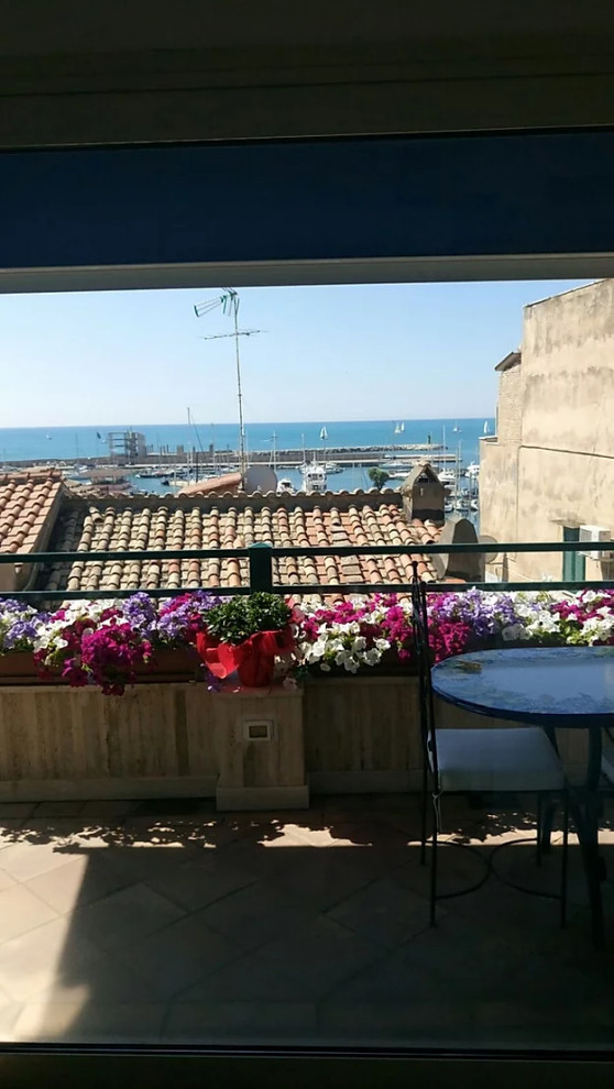 Foto di un piccolo privacy sul balcone mediterraneo con un parasole e parapetto in materiali misti
