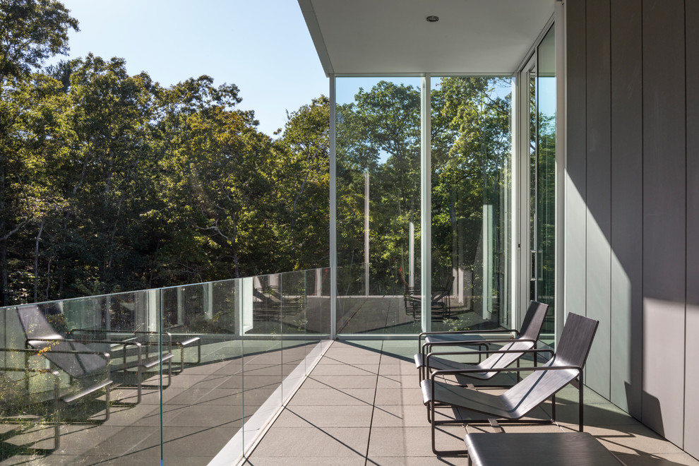 Ispirazione per un balcone minimalista di medie dimensioni con un tetto a sbalzo e parapetto in vetro