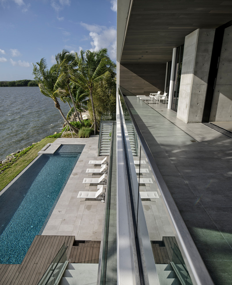 Design ideas for a large modern glass railing balcony in Miami with a roof extension.
