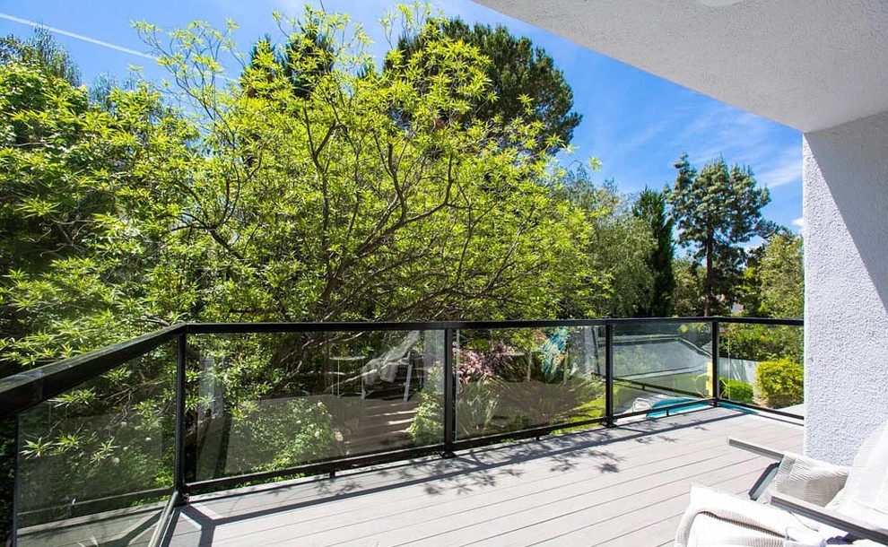 Cette photo montre un balcon moderne de taille moyenne avec une extension de toiture et un garde-corps en verre.