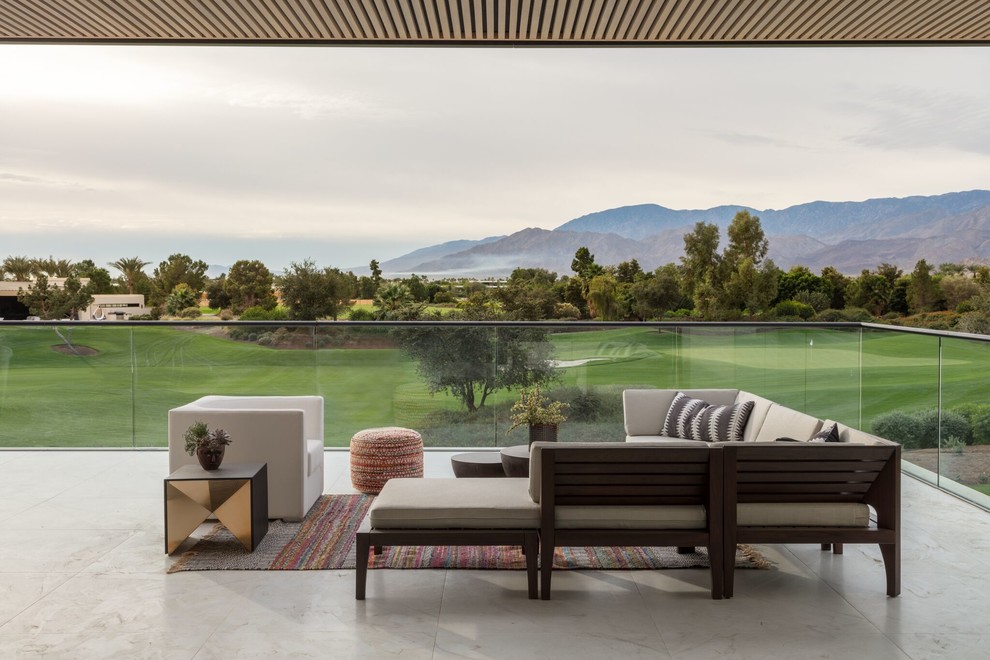 Esempio di un grande balcone design con un tetto a sbalzo e parapetto in vetro