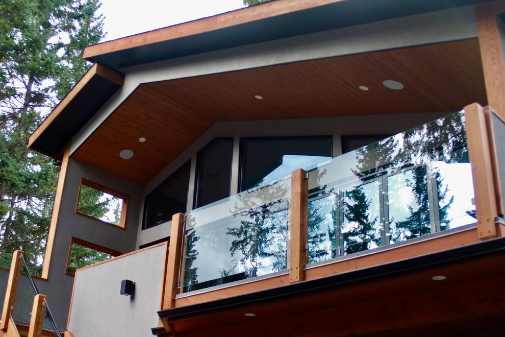 Photo of a medium sized rustic glass railing balcony in Calgary with a roof extension.