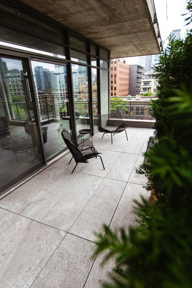 Idée de décoration pour un petit balcon design avec des plantes en pot, une extension de toiture et un garde-corps en verre.