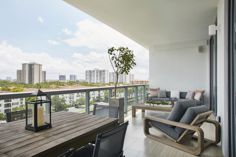 Aménagement d'un grand balcon moderne avec une extension de toiture et un garde-corps en verre.