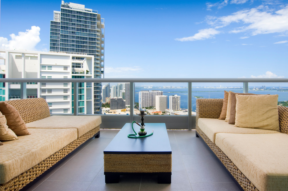 Cette image montre un grand balcon minimaliste d'appartement avec une extension de toiture et un garde-corps en métal.