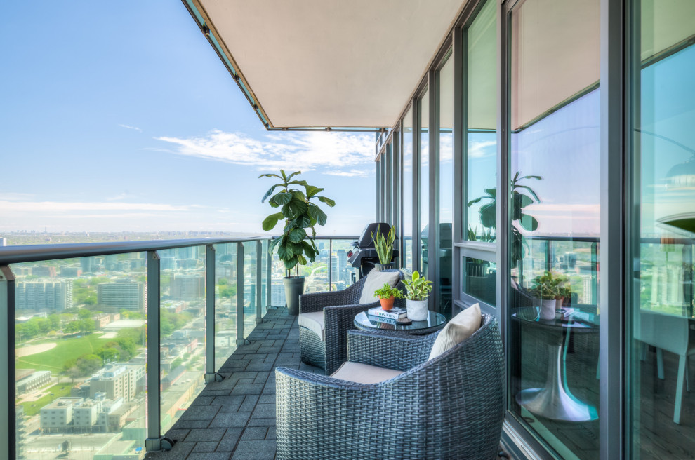 Idées déco pour un balcon moderne de taille moyenne et d'appartement avec un garde-corps en verre.