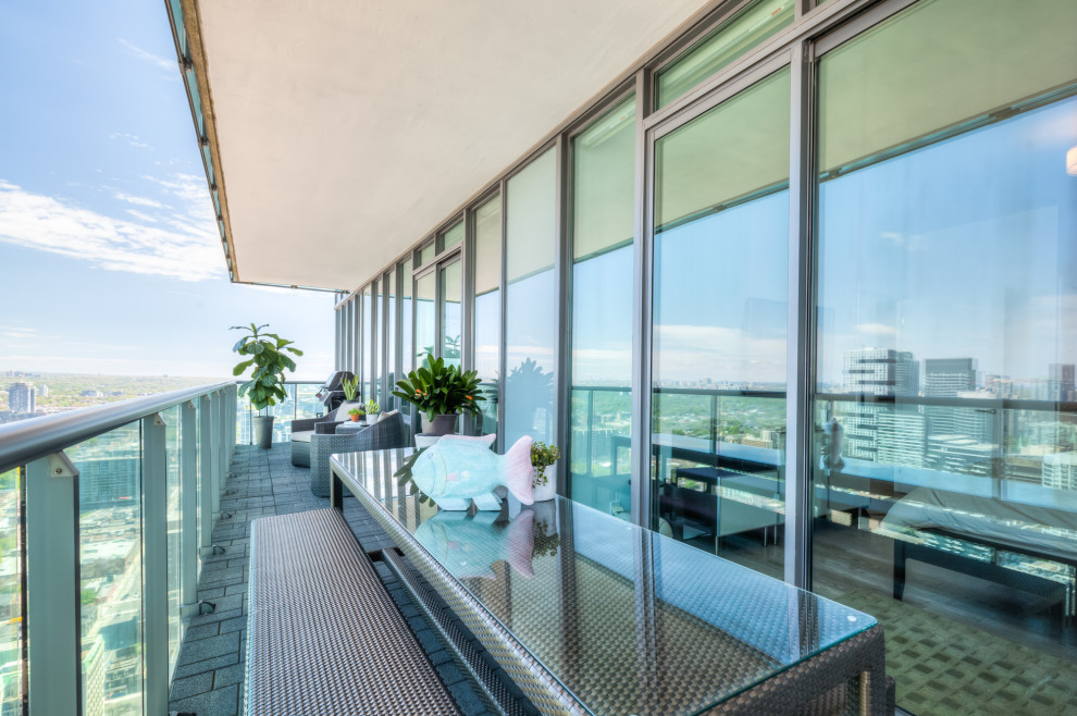 Exemple d'un balcon moderne de taille moyenne et d'appartement avec un garde-corps en verre.