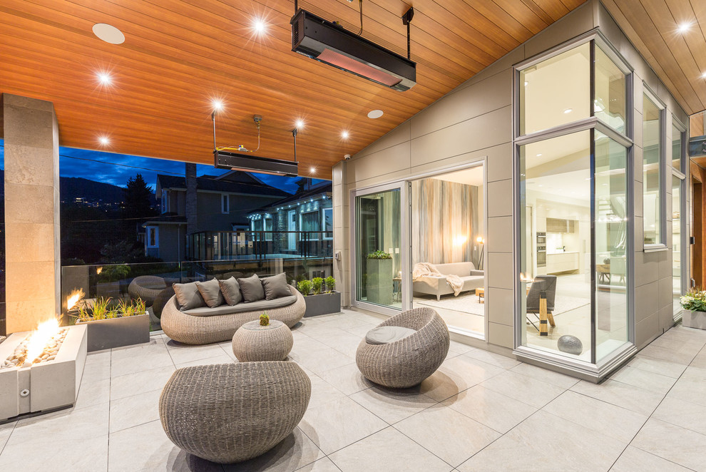 Immagine di un grande patio o portico minimalista con un focolare e un tetto a sbalzo