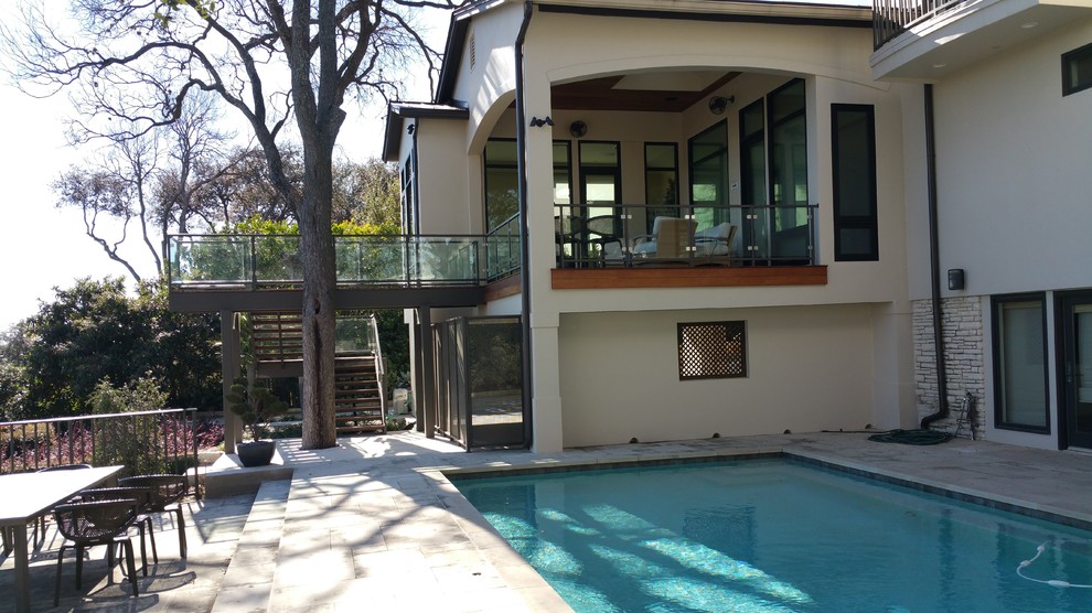 This is an example of a small bohemian glass railing balcony in Austin with a roof extension.