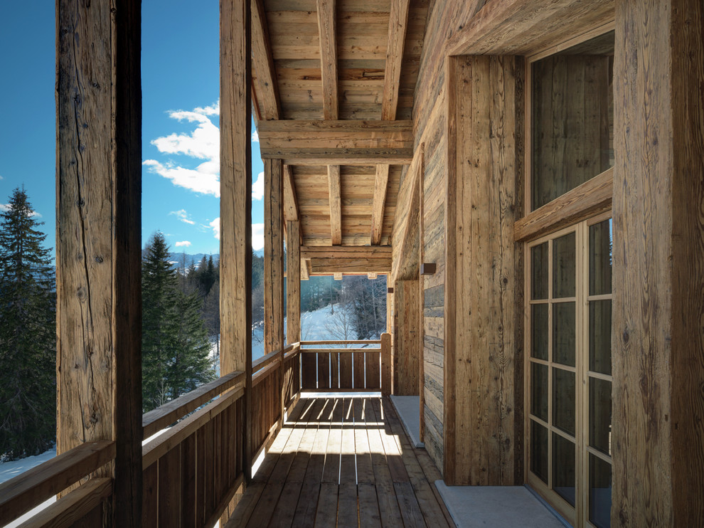 Idee per un grande balcone stile rurale con un tetto a sbalzo e parapetto in legno