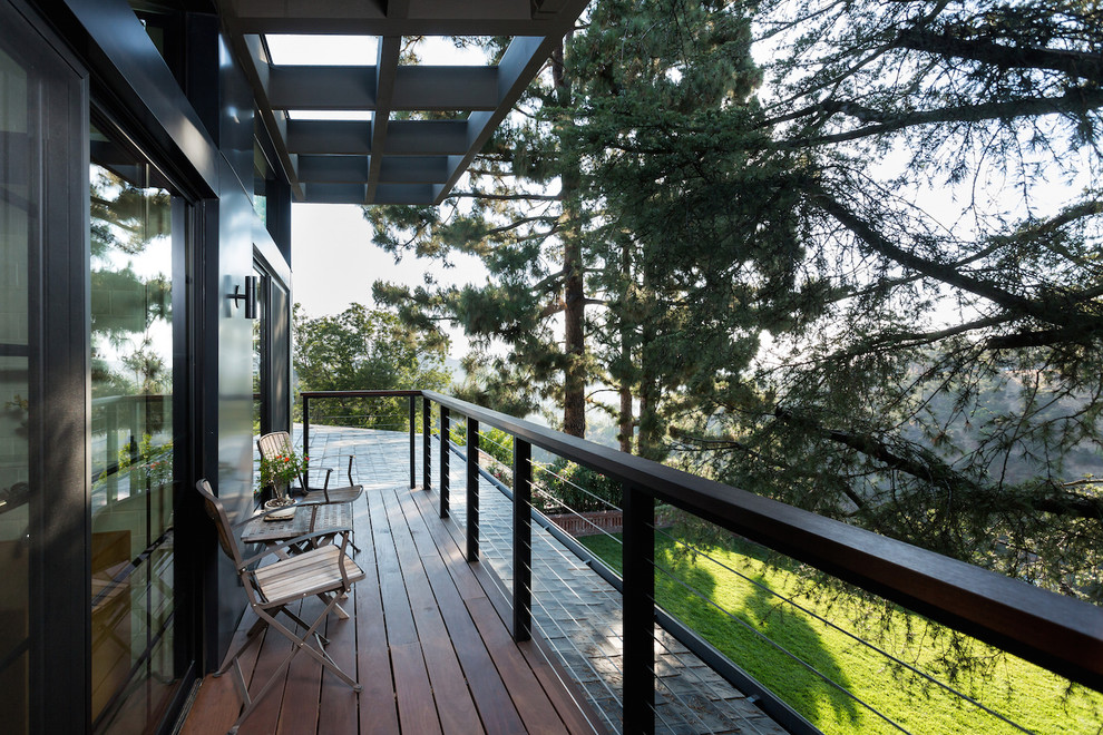 Photo of a large midcentury mixed railing balcony in Los Angeles with a roof extension.