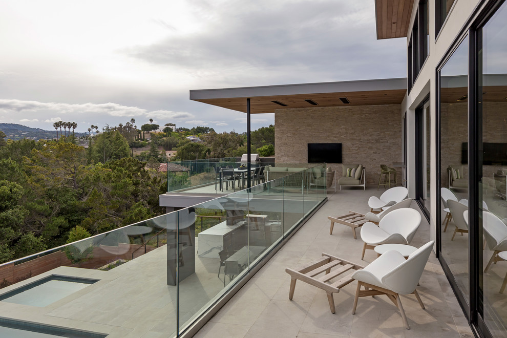 Exemple d'un grand balcon moderne avec un garde-corps en verre.