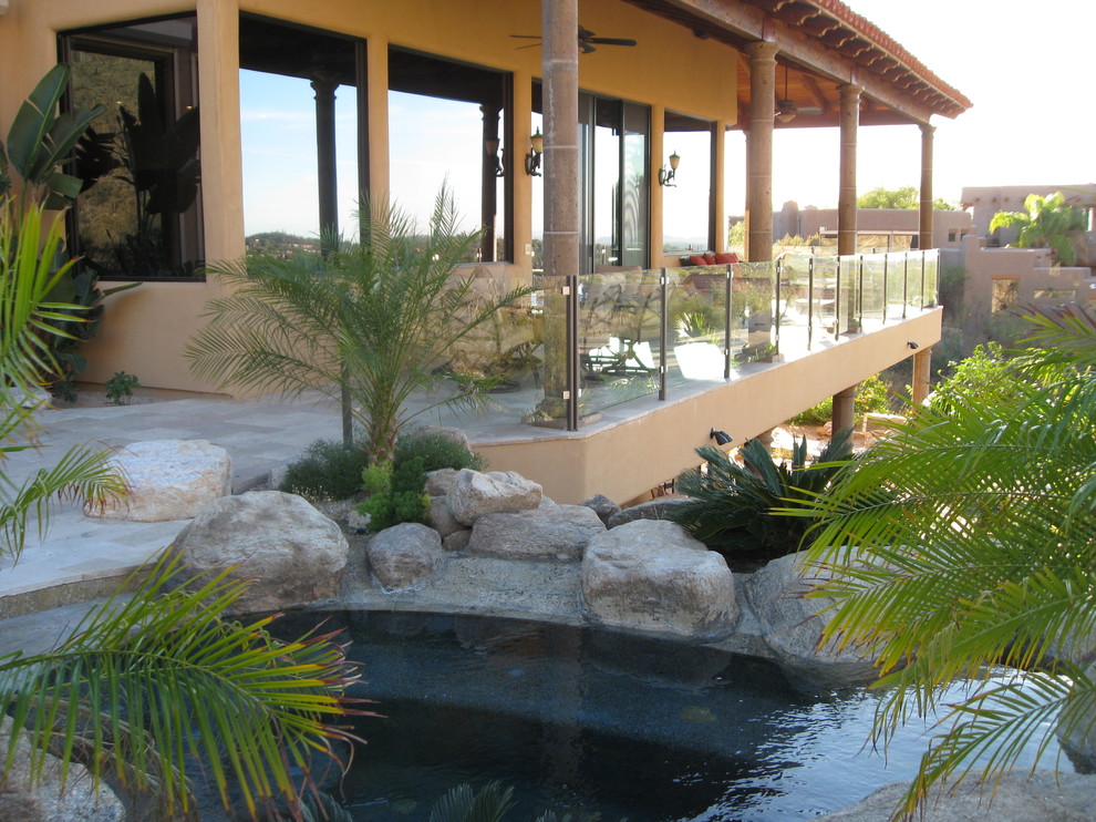This is an example of a medium sized mediterranean glass railing balcony in Phoenix with a roof extension.