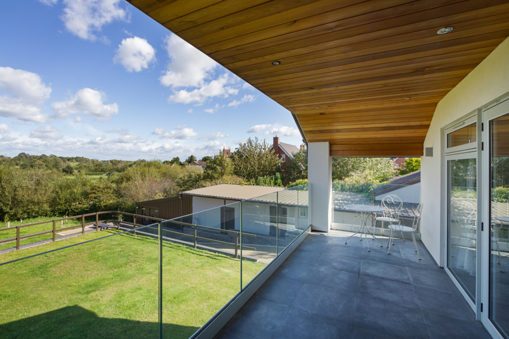 Inspiration pour un très grand balcon minimaliste avec des solutions pour vis-à-vis, une extension de toiture et un garde-corps en verre.